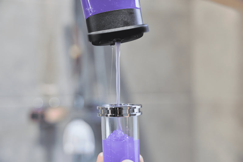 Purple liquid soap being poured from a bottle into a Soap Shower refill